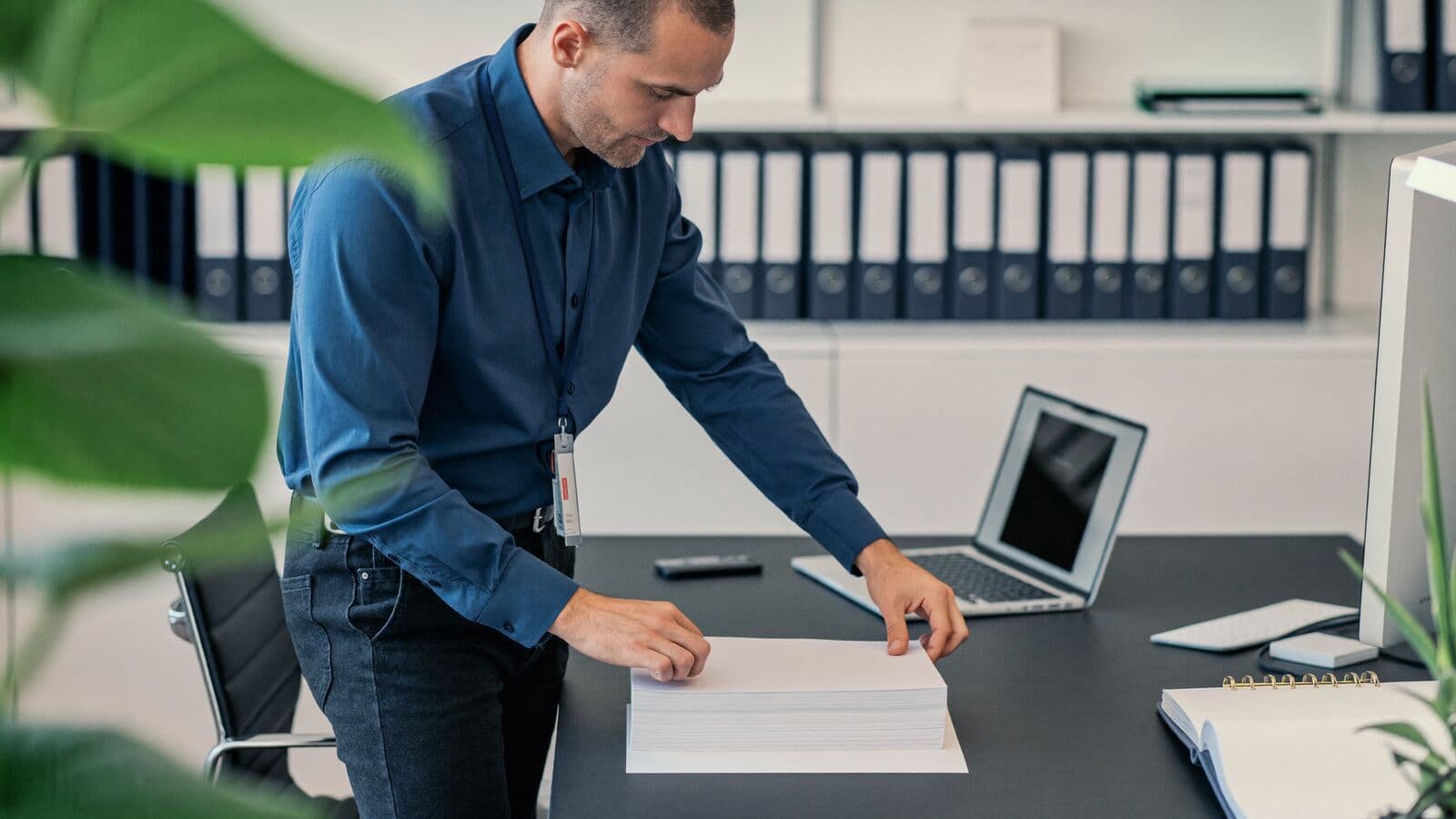 Operations lead organising documents at a desk in front of labelled binders