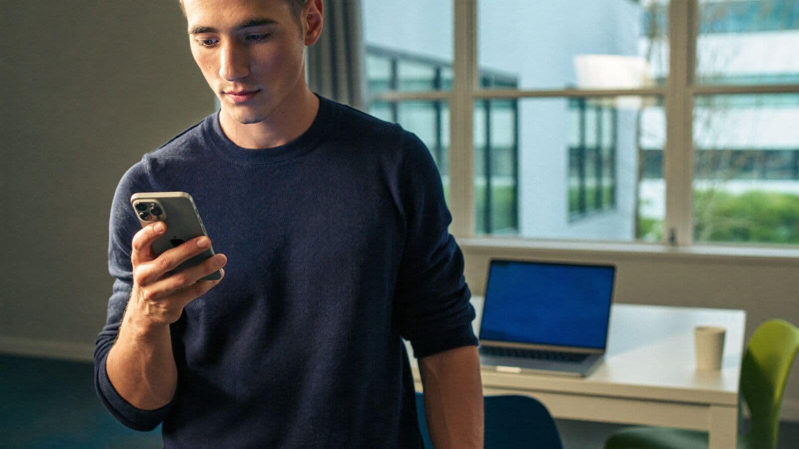 Sales coordinator checking a new enquiry on his phone in a bright office