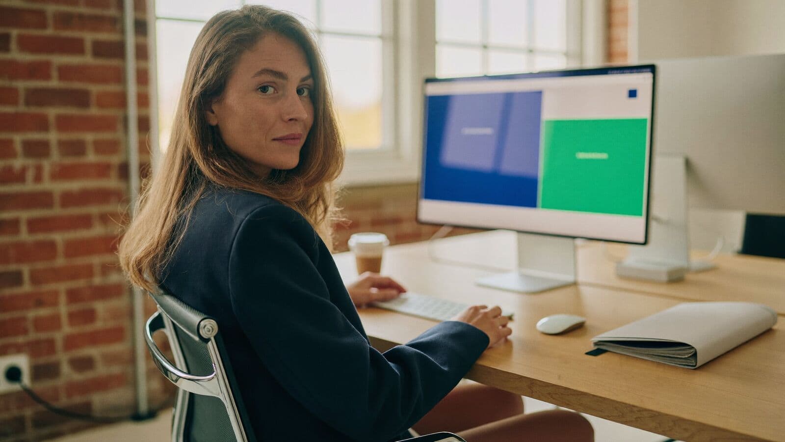 Agency owner reviewing a client portal on a desktop monitor in a brick-walled office
